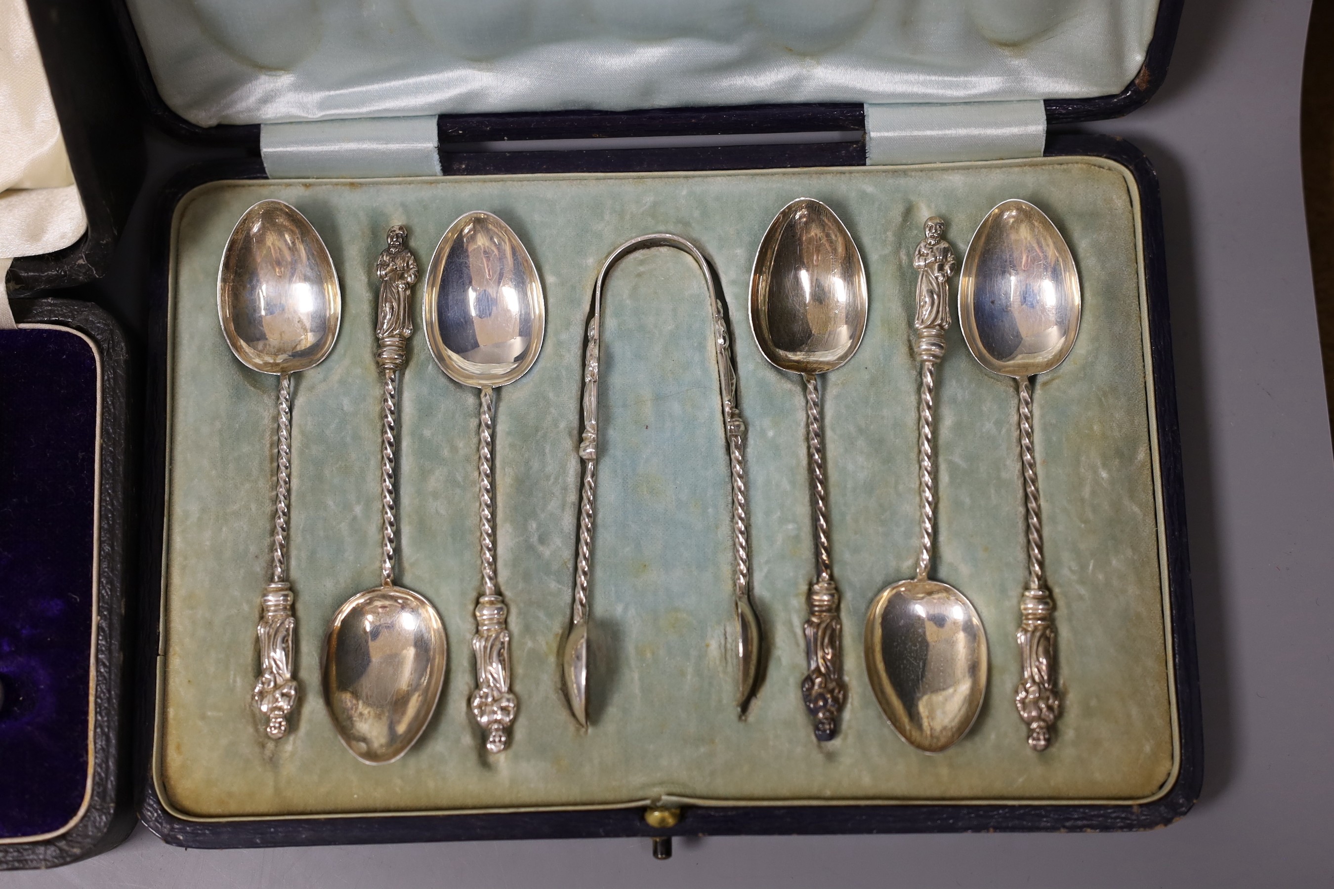 Two cased silver Christening sets, egg cup and spoon and pusher and spoon, a cased set of acanthus terminal coffee spoons, and a cased set of six apostle teaspoons and tongs, 7oz.